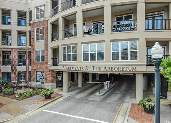 The Arboretum Apartments building has a brick facade and is surrounded by greenery.