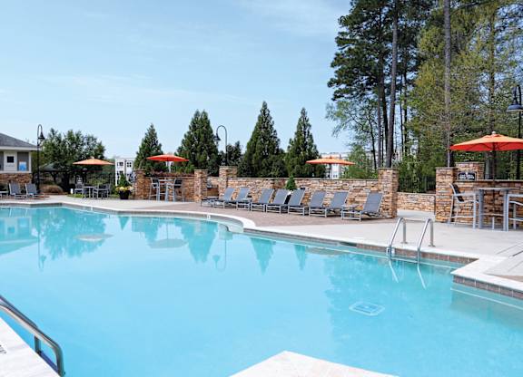 A large swimming pool with a metal ladder and a small building in the background.