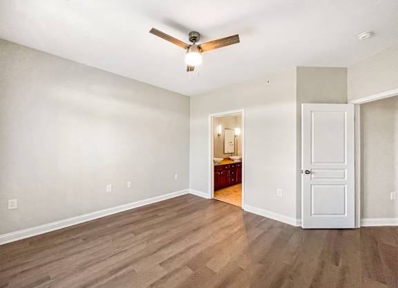 A room with a ceiling fan and wooden flooring.