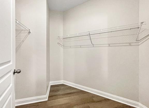 A white closet with a door and shelves.