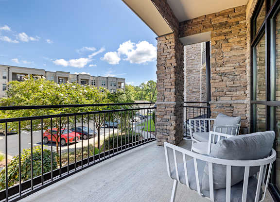 A balcony with a grey sofa and a stone pillar.