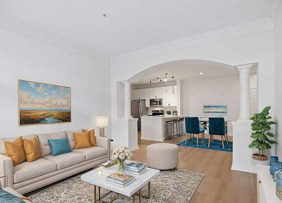 A living room with a beige couch, a coffee table, and a painting on the wall.