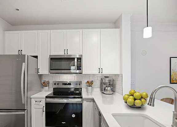 A modern kitchen with a stainless steel refrigerator and a black stove top oven.