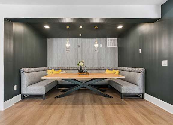 A modern dining area with a grey sofa and a wooden table.