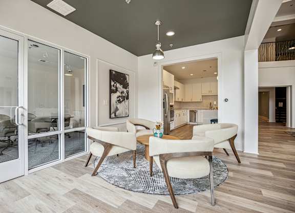 A modern dining room with a glass door leading to a kitchen.