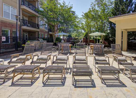 A patio with chairs and tables is surrounded by trees and buildings.