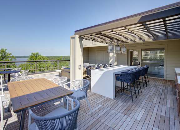 A wooden deck with a table and chairs overlooking a body of water.