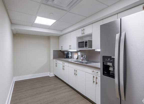 A kitchen with a refrigerator, microwave, and sink.