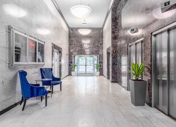 A hallway with blue chairs and a plant in a pot.