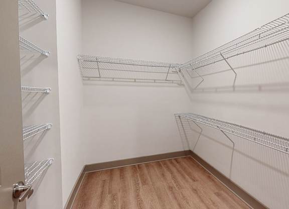 A walk-in closet with wooden floors and metal wire shelving.
