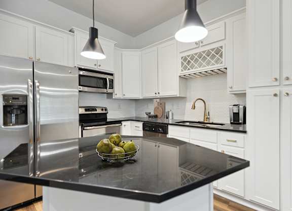 A modern kitchen with a black granite countertop and stainless steel appliances.