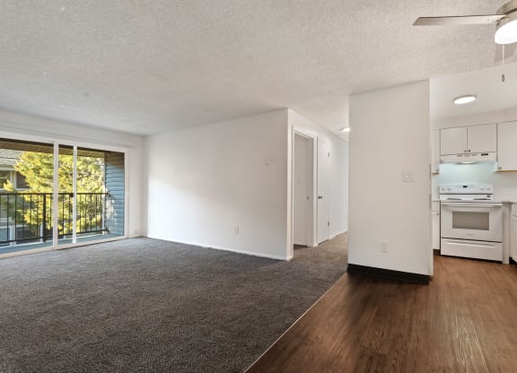 the living room and kitchen of an apartment with white appliances and wood flooring