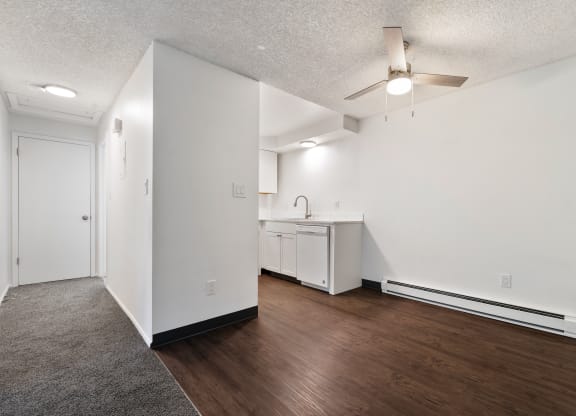 an empty living room and kitchen with white walls and wood flooring
