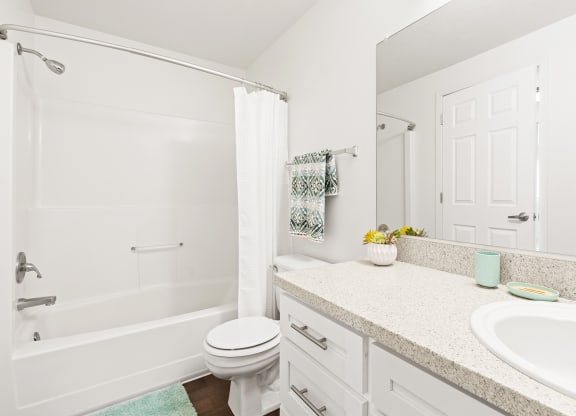 White bathroom with new white cabinets, large mirror, white toilet and full size bathtub.at North Pointe, Post Falls, 83854