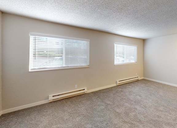 Bright one-bedroom layout at Peak 88 Apartments Renton with two windows allowing natural light and plush carpeting.