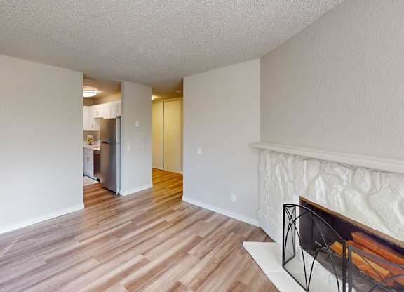 Open-concept living space at Peak 88 Apartments Renton featuring wood-style flooring, fireplace, and sliding doors to balcony.