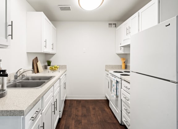 A galley-style kitchen with white cabinets and appliances and new countertops.at North Pointe, Post Falls Idaho