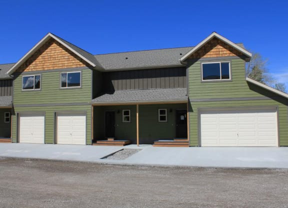 the front of a green house with two garage doors at Copper Pines, Bozeman, MT