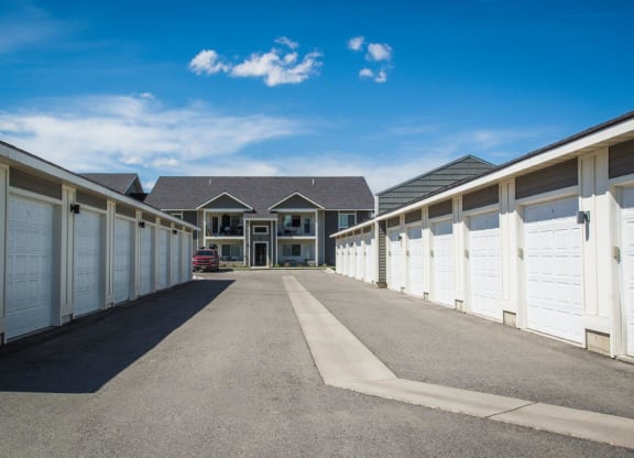 a row of garages with white doors and a house in the background at Madison Park, Bozeman, MT, 59718