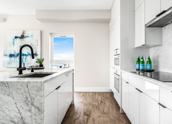 a kitchen with marble counter tops and white cabinets  at Oslo, Seattle, 98102