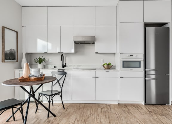 a white kitchen with a small table and a refrigerator  at Oslo, Seattle, 98102