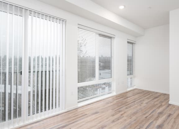 an empty living room with large windows and a wood floor at The Loop at Green Lake, Washington