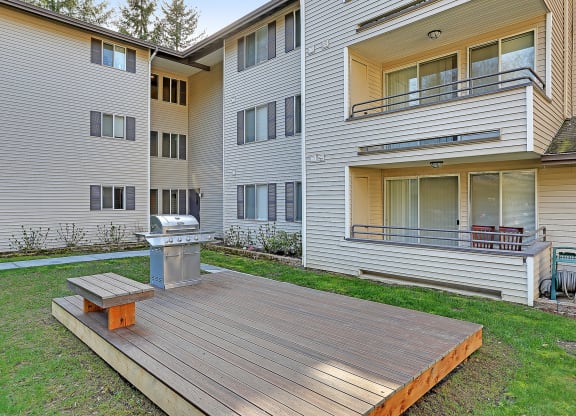 the backyard of an apartment building with a wooden deck and a fire pit  at Townside Flats, Redmond