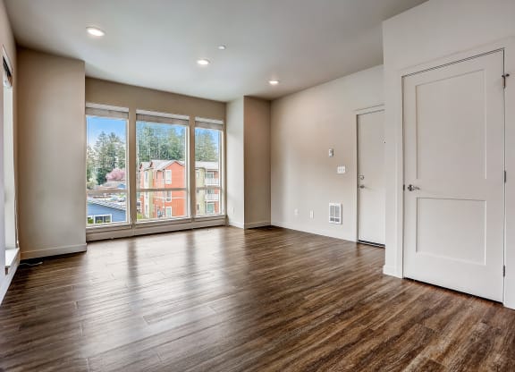 an empty living room with a large window and wooden floors at Woodcreek, Poulsbo