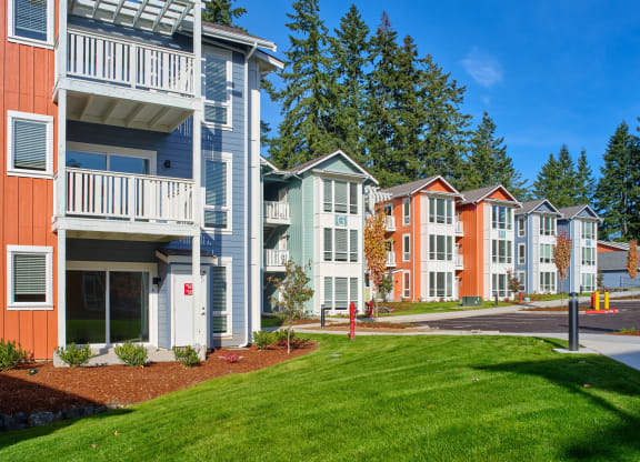 an exterior view of a row of apartment buildings with green grass at Woodcreek, Poulsbo Washington