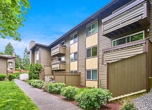 Exterior view of personal patios or balconies, manicured grounds and building, and blue skies in the background at Heritage Grove, Renton, WA.