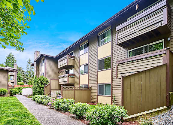 Exterior view of personal patios or balconies, manicured grounds and building, and blue skies in the background at Heritage Grove, Renton, WA.