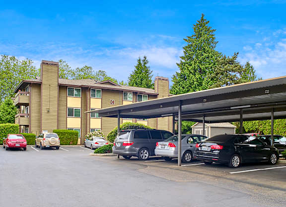 a parking lot with covered parking in front of Heritage Grove Apartments in Renton, WA