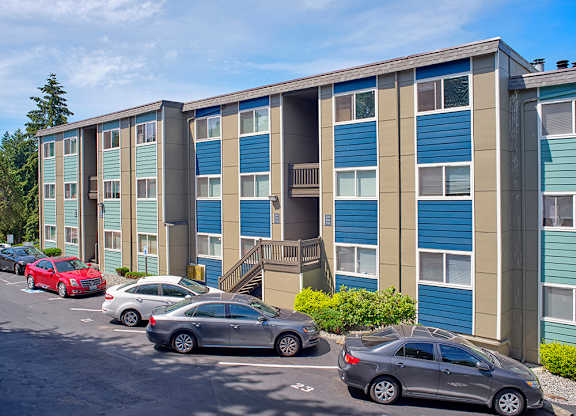 Community apartments painted shades of blue and beige with parked cars along the landscaped path.