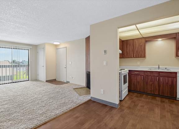 A spacious living room with a kitchenette and sliding glass doors.