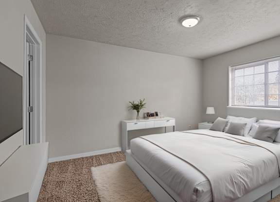 Staged bedroom at The Overlook Apartments in Post Falls featuring a large bed, nightstand, and bright natural light.