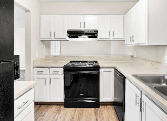 Modern kitchen at The Overlook at Falls Park Apartments in Post Falls, ID, featuring white cabinetry and a black dishwasher.