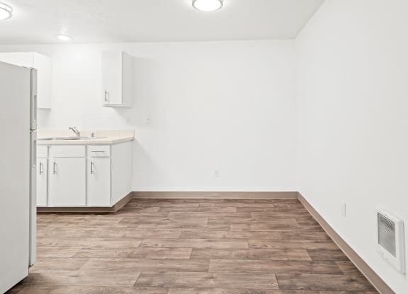 Bright dining area with faux wood floors and white walls. Kitchen with new white cabinets is visible to the left.at North Pointe, Post Falls, ID 83854