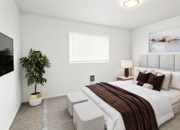 a large bedroom with white walls, a window on back wall and carpet. Staged with a queen-sized bed, side tables, a plant and a flat screen TV.at North Pointe, Idaho, 83854
