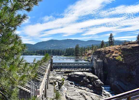 A dam on a river with a mountain in the background.