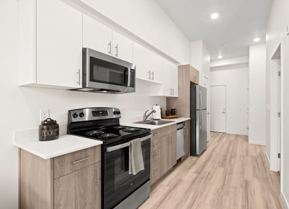 a kitchen with white cabinets and black appliances at The Duo, University Place, WA