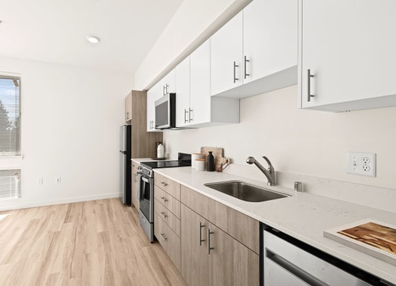 a renovated kitchen with white cabinets and a sink at The Duo, University Place, WA 98466