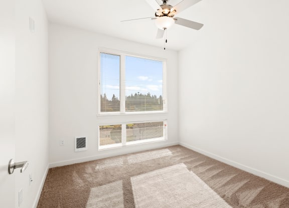 a bedroom with a large window and a ceiling fan at The Duo, University Place, WA