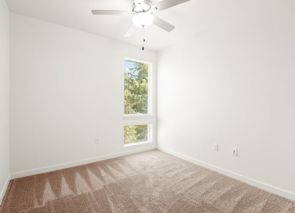 an empty room with a window and a ceiling fan at The Duo, University Place, WA 98466