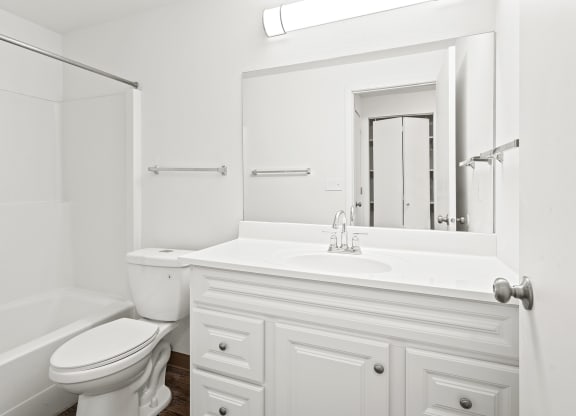 White bathroom with new white cabinets, large mirror, white toilet and full size bathtub.at North Pointe, Post Falls