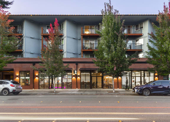 Building exterior at dusk with large green trees and balconies at 6 Wood Flats, Lacey Washington