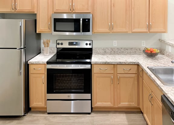 Corner style kitchen with wood cabinets and a stainless steel stove and microwave at 6 Wood Flats, Washington, 98503