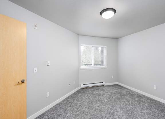 Large bedroom with plush carpet and bright window in a 728 square foot apartment at 6Wood Flats Lacey WA