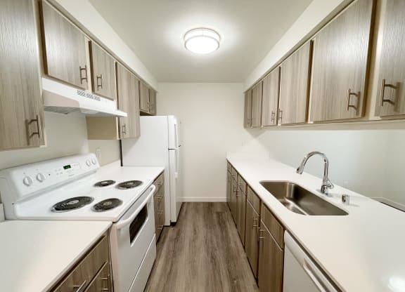 Double galley kitchen with oven, stovetop, fridge, sink, and dishwasher with a pass through window to the dining area.at The Trail, Snohomish, 98290