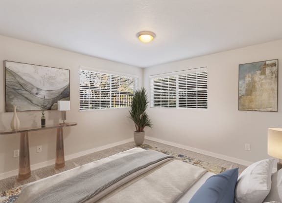 Bedroom with two large windows, staged bed, carpet, side tables and art on walls.at Capitol Crossing, Olympia