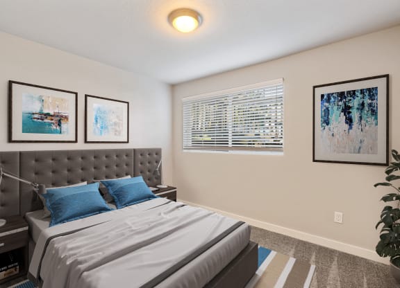 Bedroom with large window, staged bed, carpet, side tables and art above bed.at Capitol Crossing, Olympia